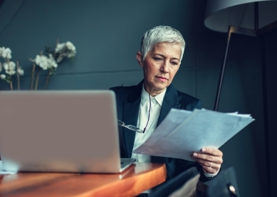 Senior woman using laptop and looking at paperwork