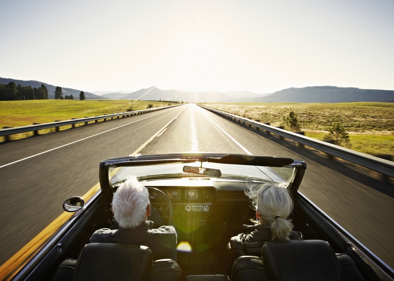 couple in a convertible riding into the sunset