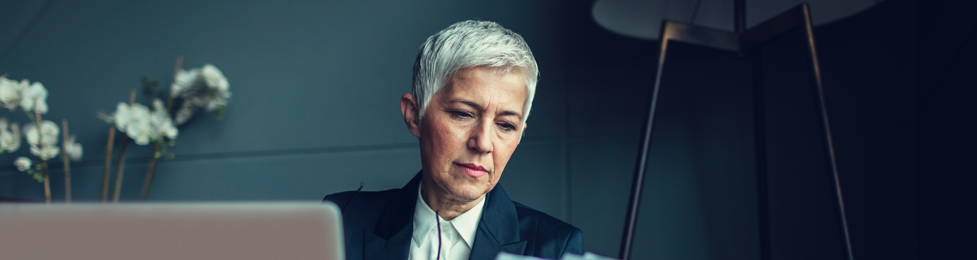 Senior woman using laptop and looking at paperwork