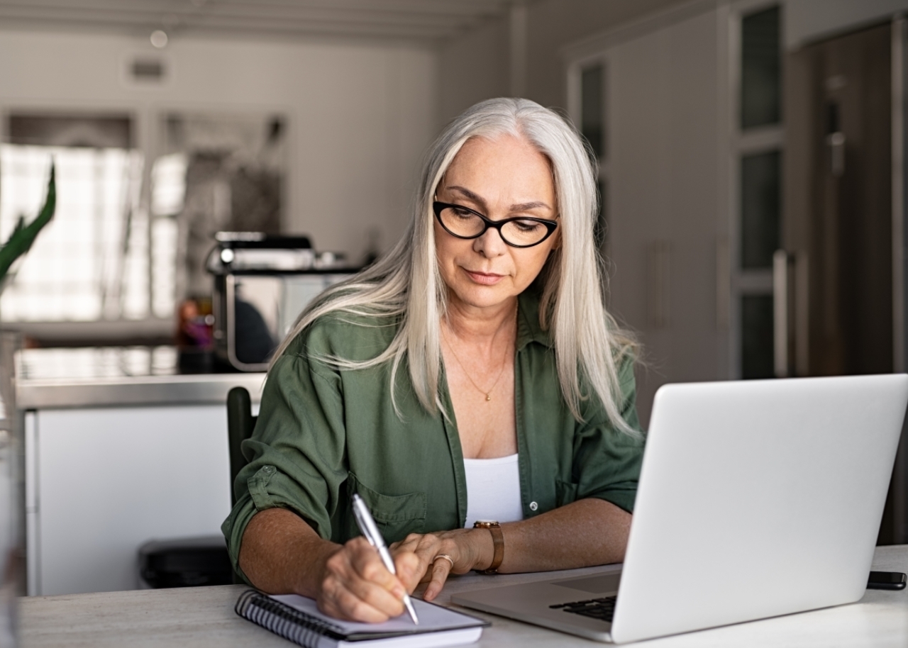 woman working on laptop and writing