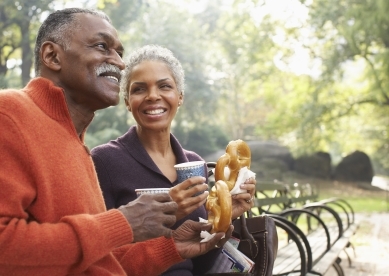 Couple eating pretzels on park bench